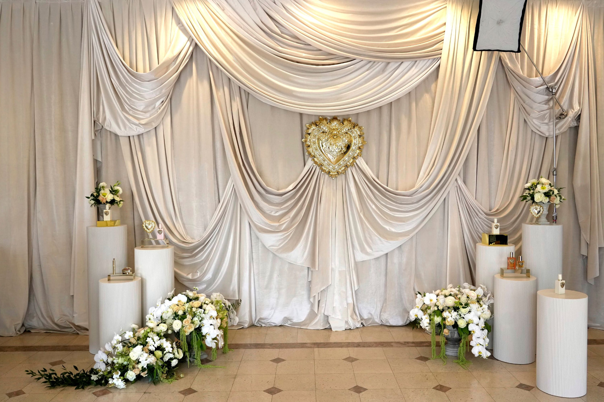 Draped backdrop with gold Devotion heart and fragrance plinths